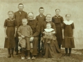 Gårdmand i Skold, Jens Jacobsen (1846-1923) fotograferet med sin hustru Kirsten Marie Jacobsen (f. Lauritsen, 1867-1946) og deres syv børn omkring 1915. Forrest hos forældrene Mads Østergaard Jacobsen (1909-1983) og Ane Marie Jacobsen (g. Haaning, 1914-2008). Stående fra venstre Johanne Jacobsen (g. Nielsen, 1904-1990), Laurits Jacobsen (f. Lauritsen, 1896-1983), Jacob Jacobsen (1899-1936), Kirsten Johanne Kathrine Jacobsen (g. 'Crone' Christensen, 1902-1992) og Mariane Meldgaard Jacobsen (g. Kristensen, 1907-1980).