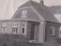 Vind Stationsby: Ejendommen, vi i dag kender som Holstebrovej 9, fotograferet i slutningen af 1930'erne. I den ende, der vender nærmest kameraet, boede postomdeler Bertel Bertelsen (1894-1995). I den anden Christian Refstrup Gravesen (f. 1914), der fra sin forretning solgte blandt andet tobak, konfekture og cykeludstyr. Bemærk som detalje Bertelsens bil i gården bag huset. For yderligere oplysninger om Bertelsen og Gravesen, se menupunkterne 'Kender du historien om...' -> 'Den gamle post og flagalléen' og 'Vind i billeder' -> 'Månedens billede, marts 2015'.