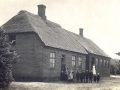 Stråsø Skole -stråtækt skolestue nærmest kameraet og tegltækt lærerbolig i baggrunden. Omkring 1910.