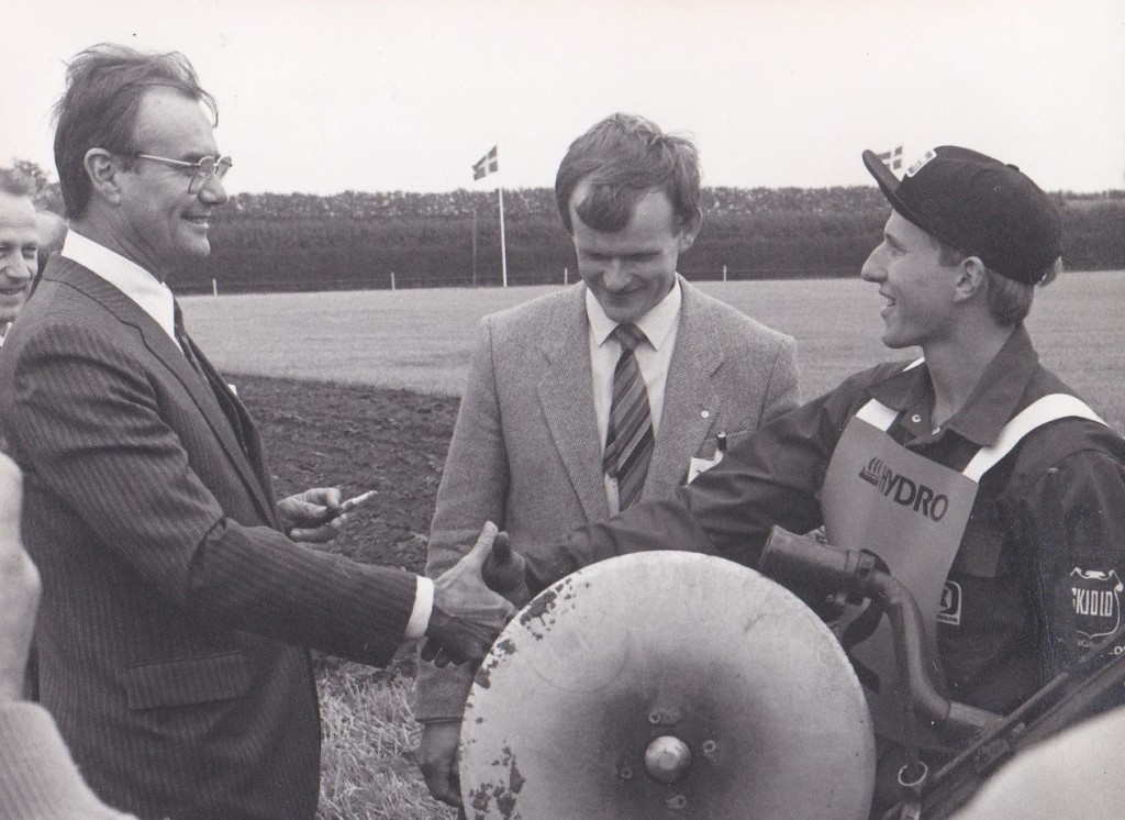 Prins Henrik hilser på 20-årige Lars Gammelvind, yngste deltager ved Verdensmesterskaberne i traktorpløjning i 1985. I midten ses daværende formand for Danmarks Landboungdom, Jens Erik Boesen.