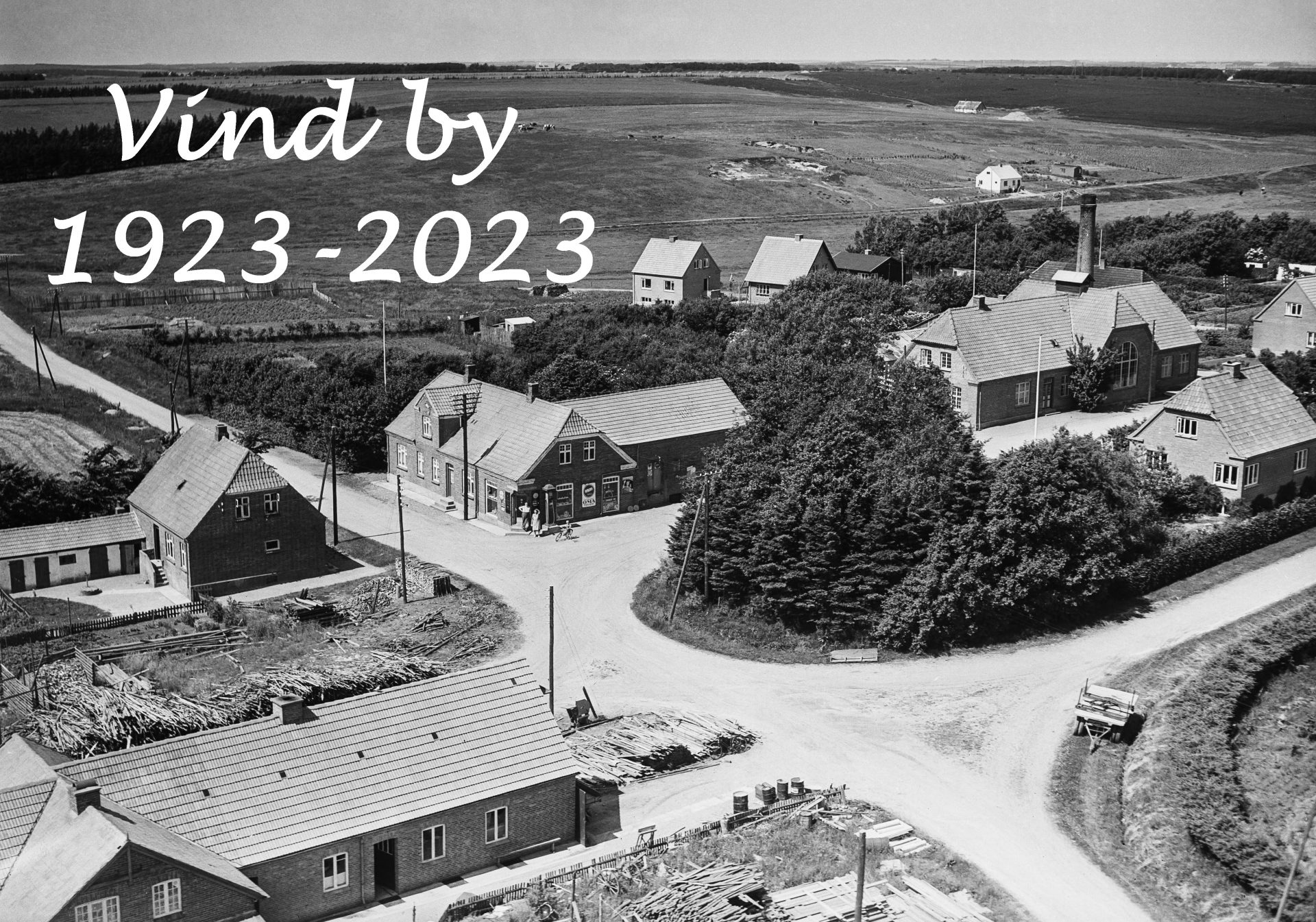 Vind Stationsby fotograferet i 1953. Midt i billedet ses Halkjærs købmandsforretning, hvis opførelse i 1923 anses for byens grundlæggelse. Kilde: Det Kgl. Biblioteks Luftfotosamling.